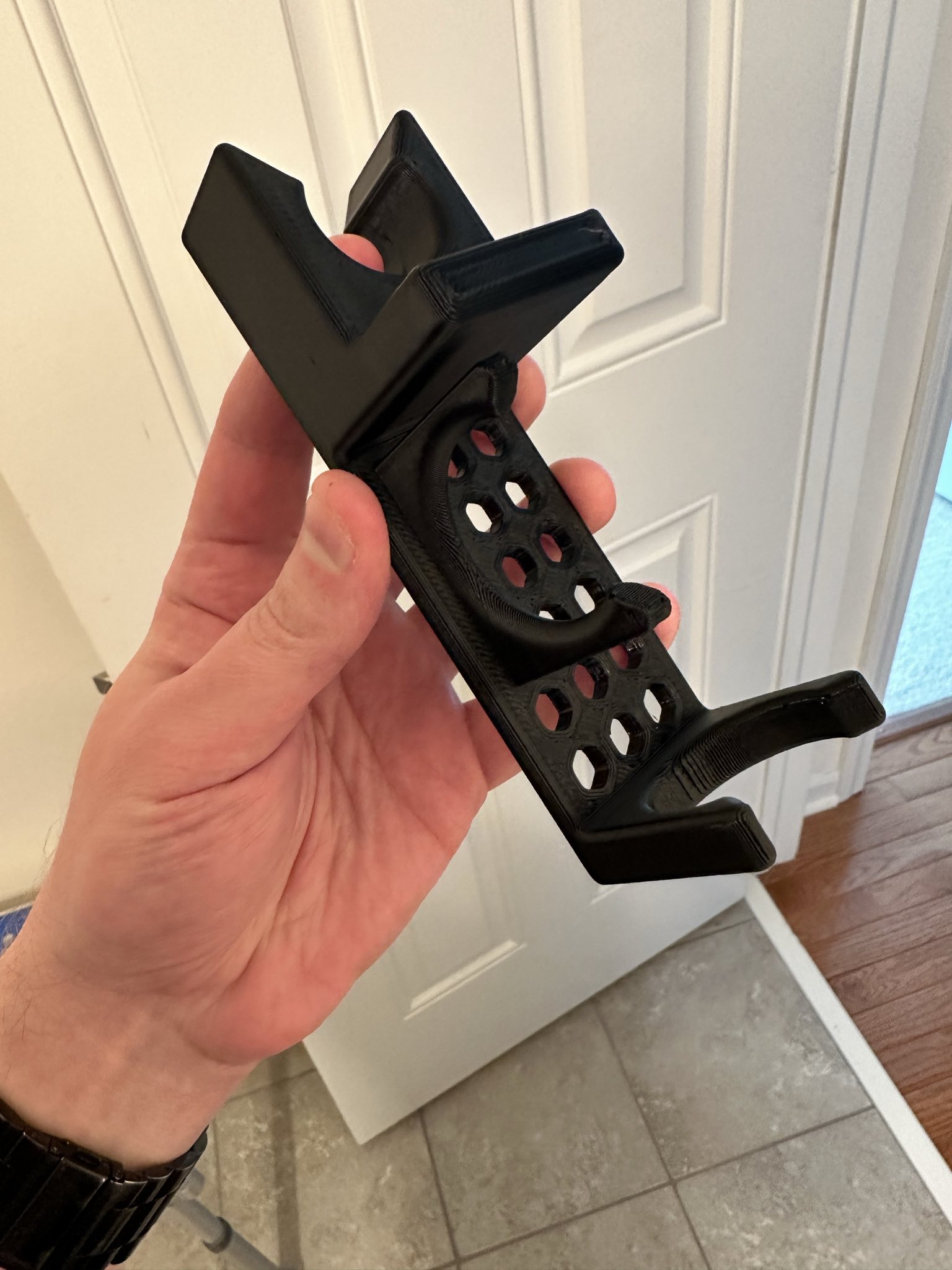 A hand holding the 3D printed shower wand grab bar mount.