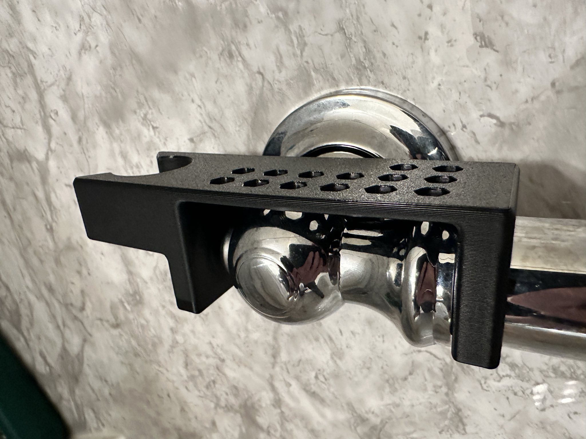 The 3D printed shower wand grab bar mount part mounted on a shower grab bar.