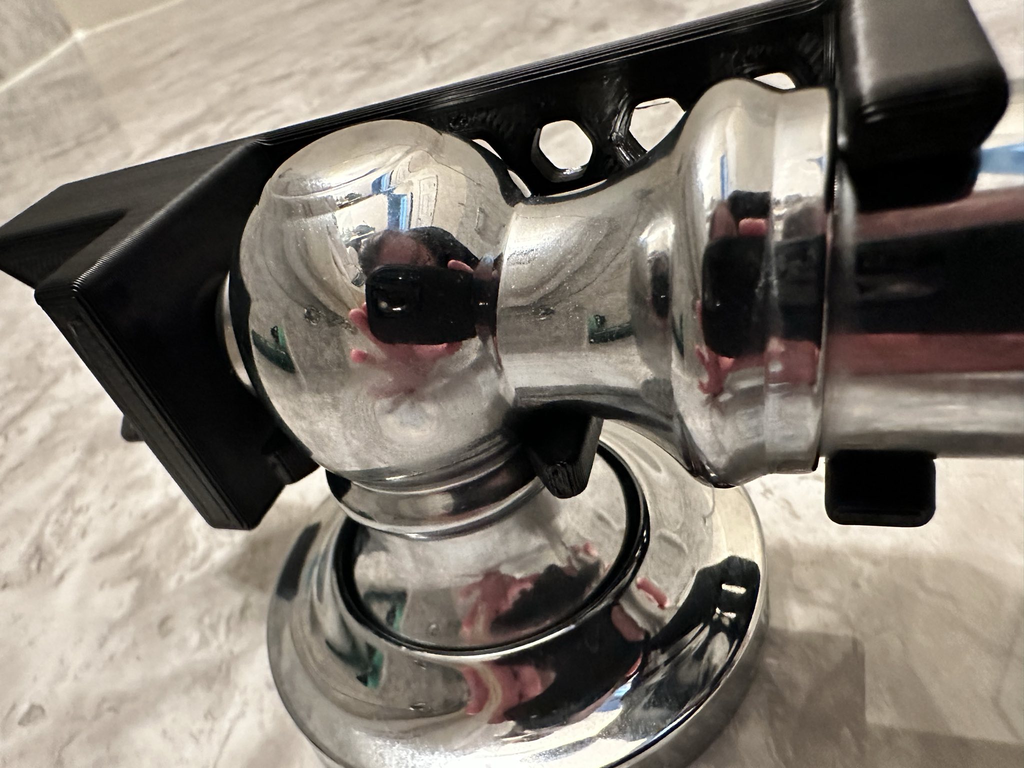 The 3D printed shower wand grab bar mount part mounted on a shower grab bar from a lower angle to show off the mounting interface.