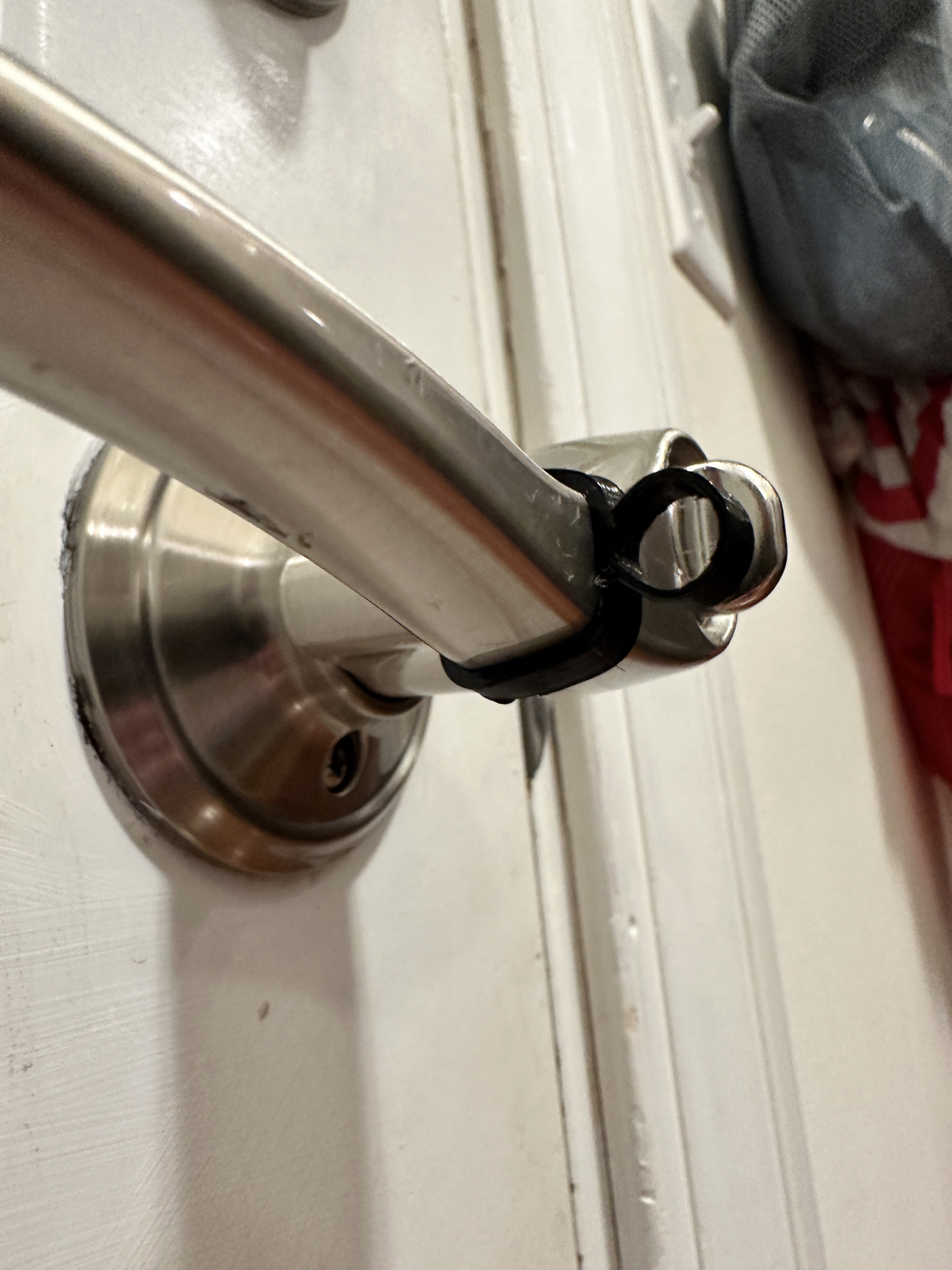 A photograph of a door handle with a stretchy plastic “shock absorber” shape stretched over one handle.