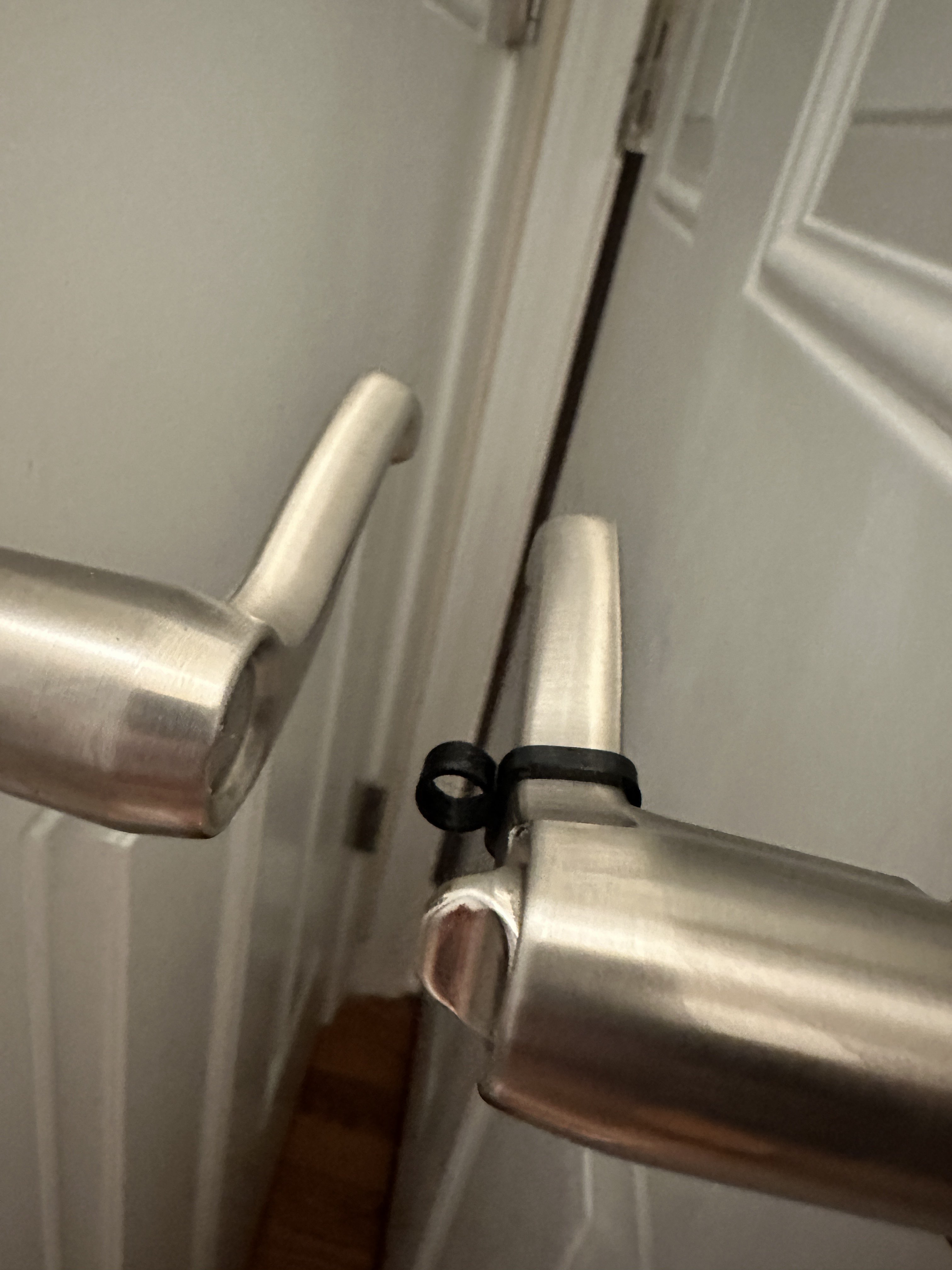 A photograph showing two door handles. One with the stretchy plastic “shock absorber” and one without. The two handles are close, but not touching.