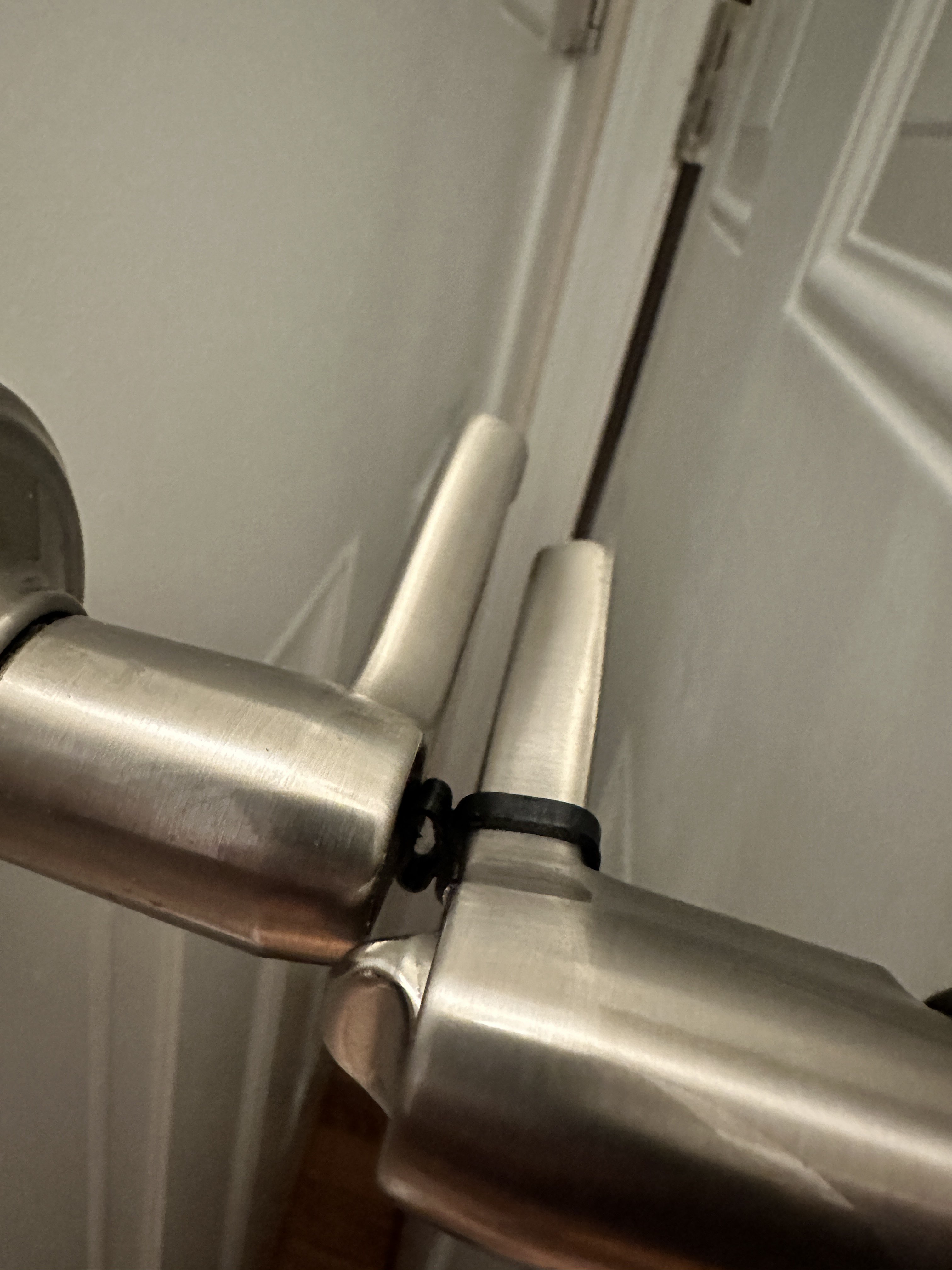 A photograph showing two door handles. One with the stretchy plastic “shock absorber” and one without. The door handles have almost collided, but the stretchy plastic “shock absorber” is compressed and the door handles themselves never touch.